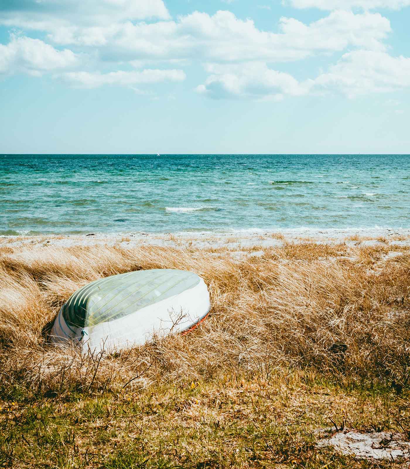 Strandbild med båt liggandes i sanden